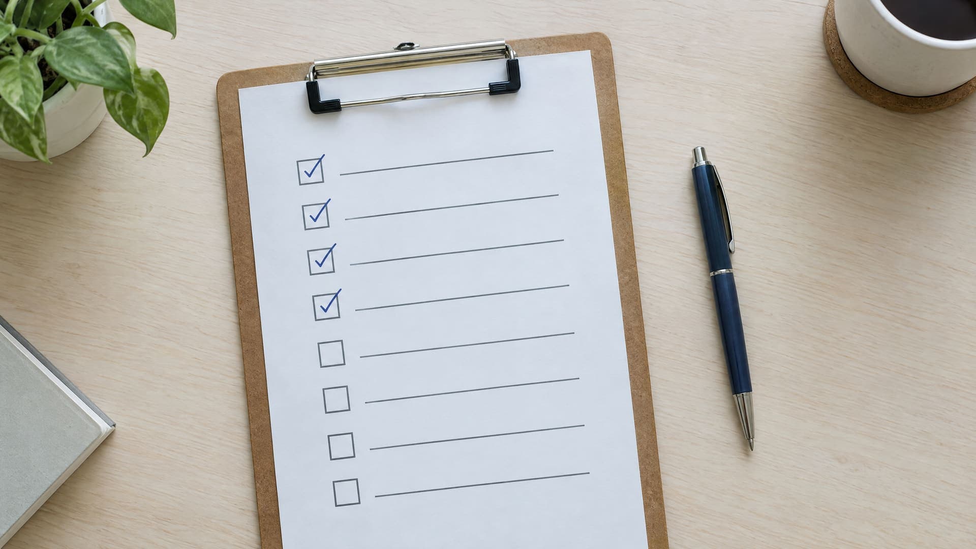 Klemmbrett mit einer Checkliste, einige Kästchen abgehakt, daneben ein Stift auf einem hellen Schreibtisch, Text unleserlich