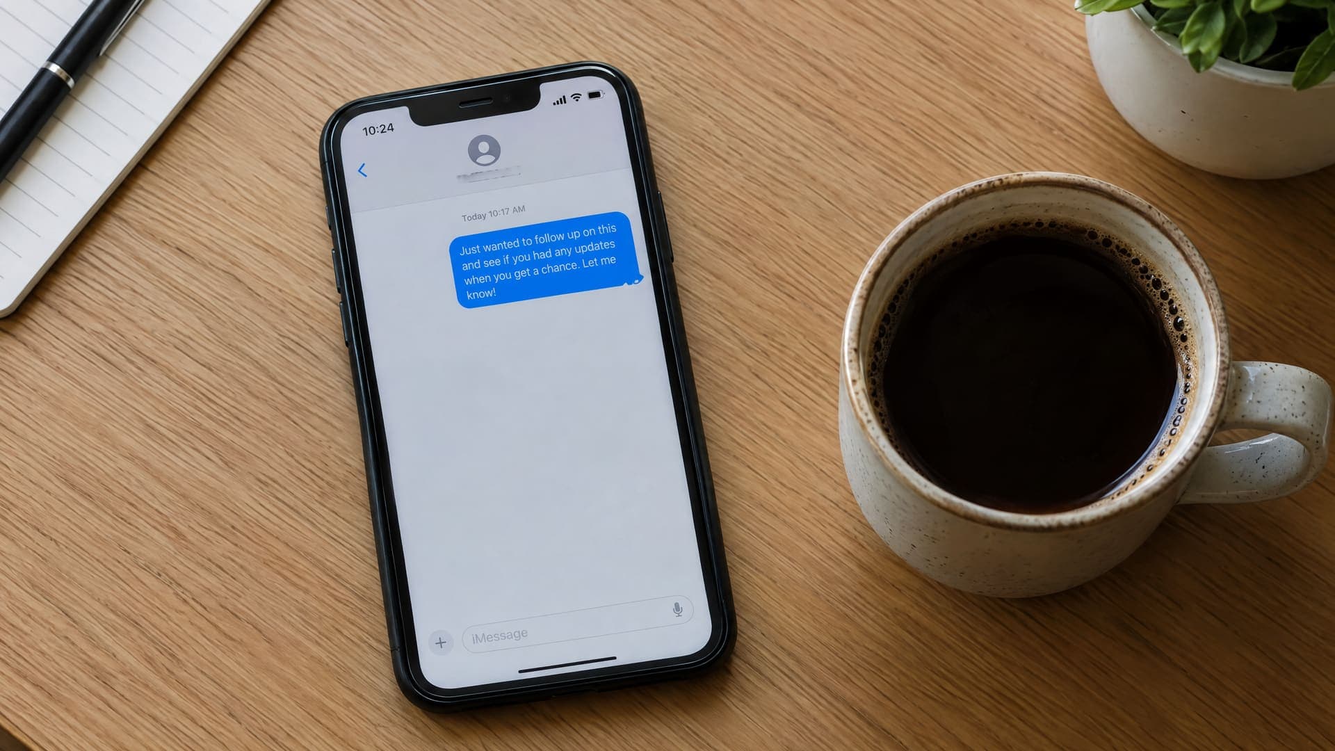 Smartphone zeigt eine kurze Nachfass-Nachricht, daneben eine Tasse Kaffee auf einem Schreibtisch, Text unleserlich