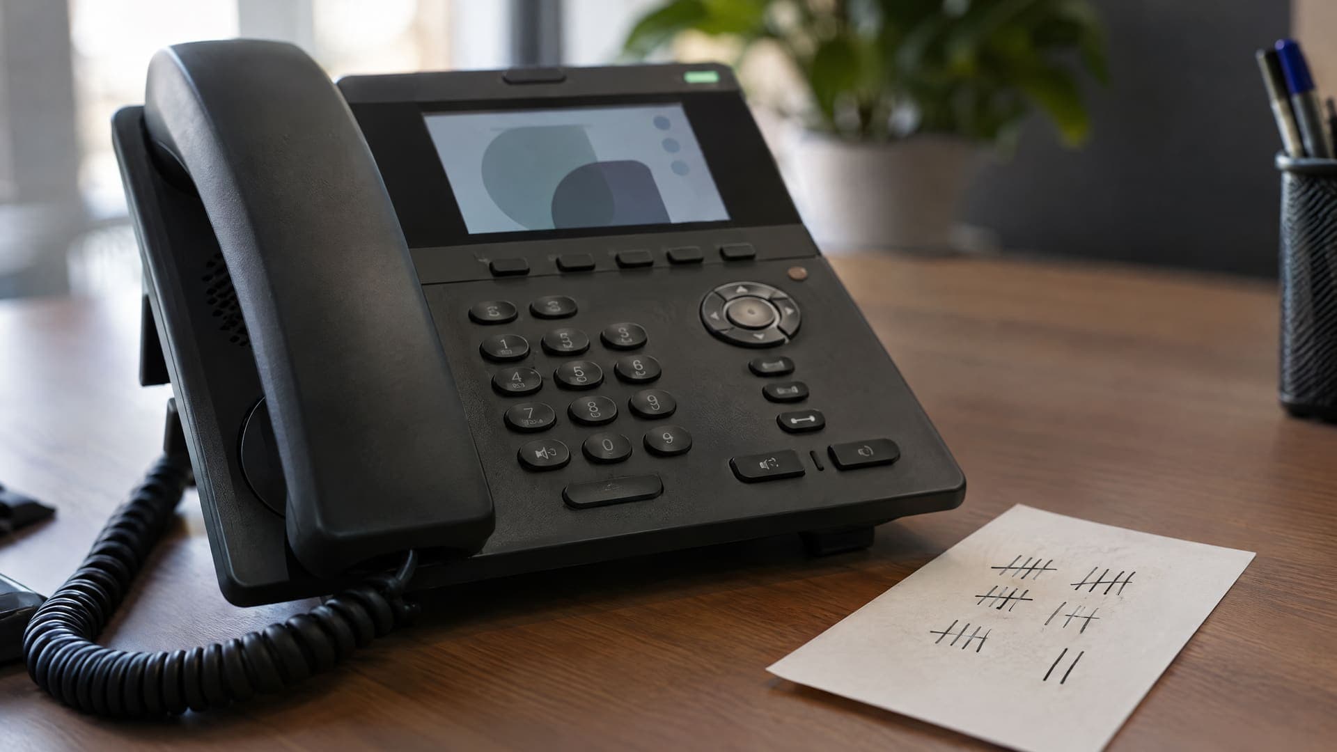 Bürotelefon neben einem Zettel mit Strichliste auf einem Schreibtisch, Striche ohne lesbare Zahlen