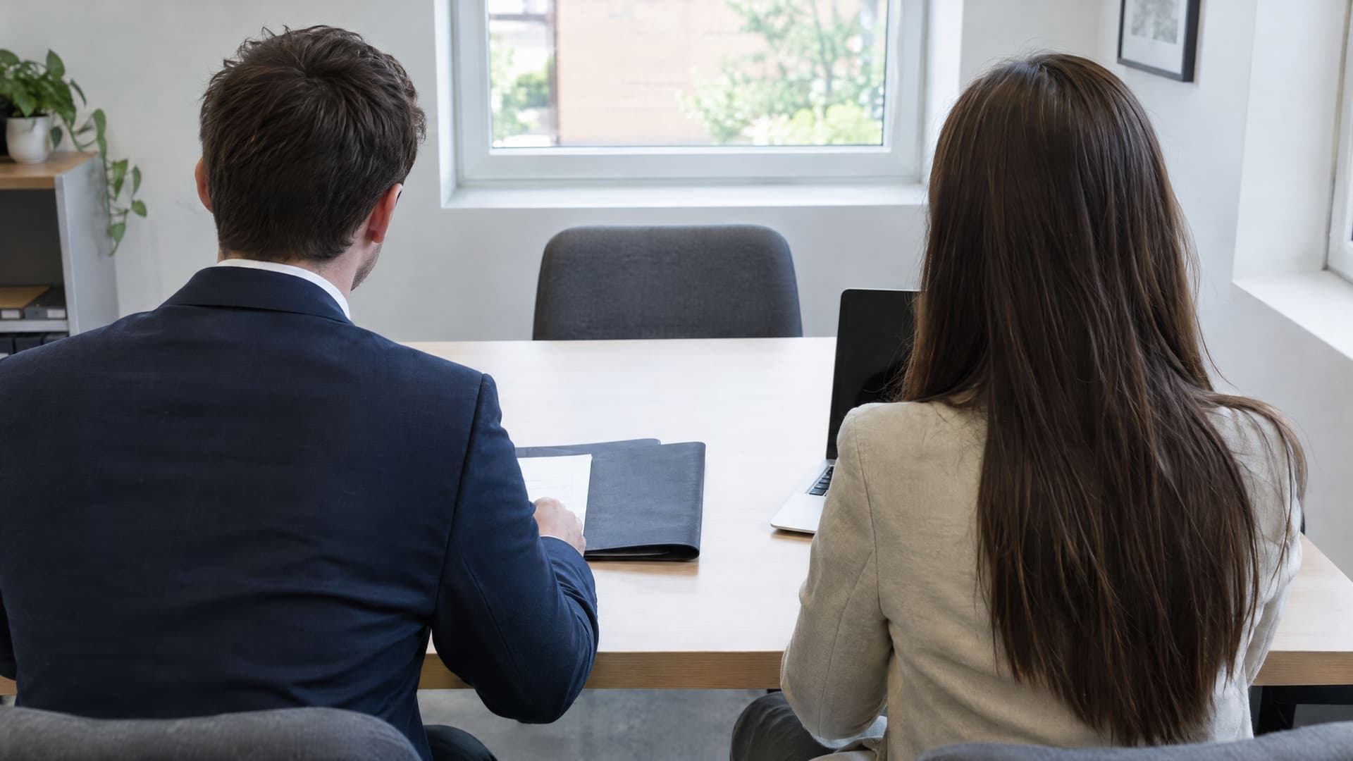 Zwei Personen von hinten an einem Tisch beim Vorstellungsgespräch