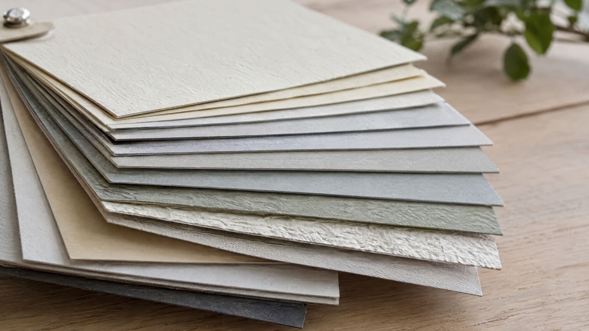 Nahaufnahme eines Fächers aus Papiermustern mit unterschiedlichen Oberflächen und Stärken in dezenten Farben, geringe Tiefenschärfe