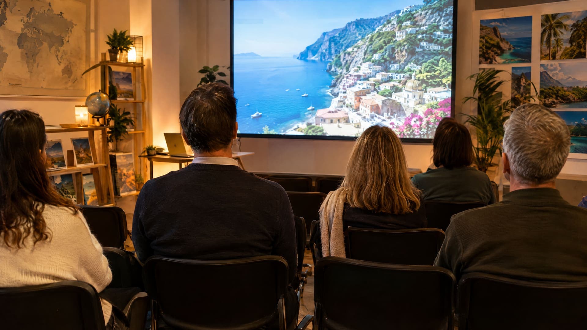 Kleiner Abend-Reisevortrag in einem Reisebüro mit Stuhlreihen, Leinwand mit Reiseziel-Foto und einigen Gästen von hinten