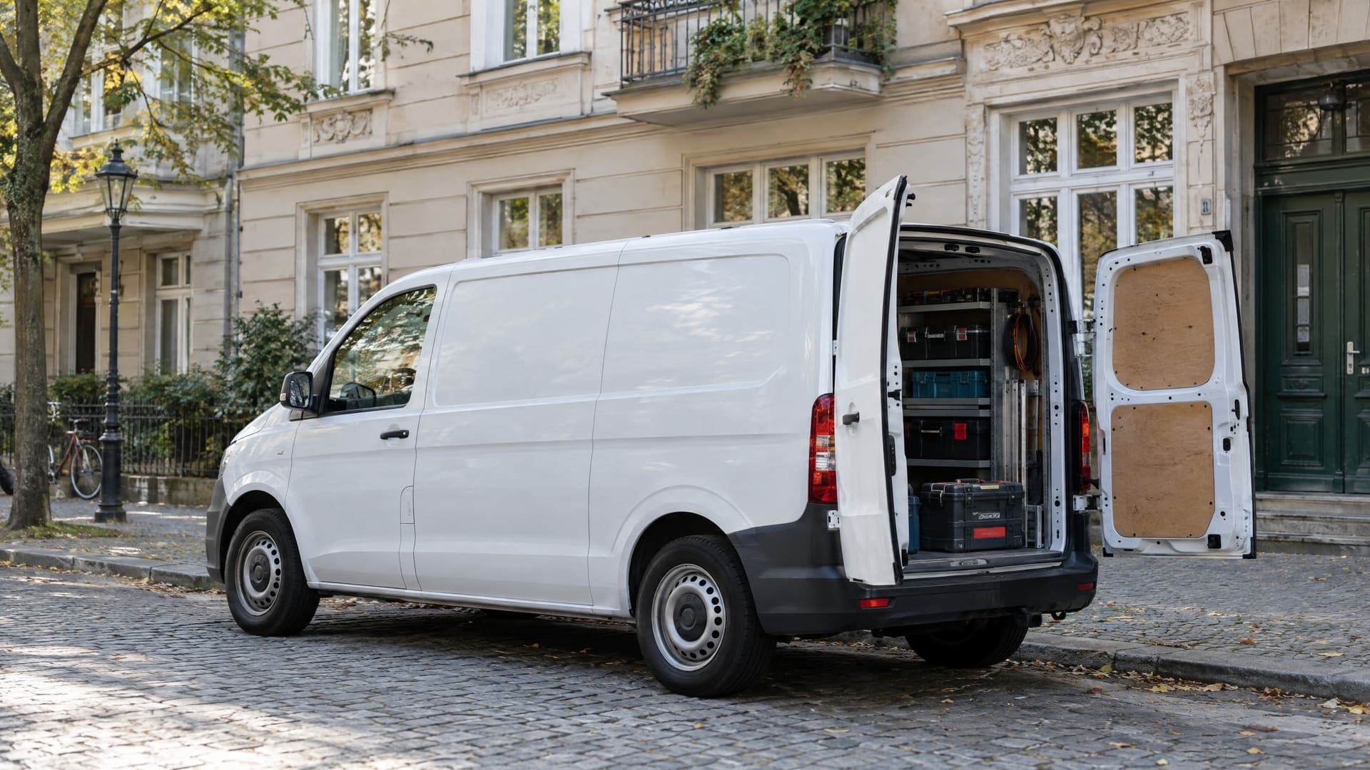 Weißer Servicewagen ohne Beschriftung vor einem Berliner Altbau im weichen Morgenlicht, im geöffneten Heck sind Werkzeugkoffer zu sehen, keine Personen